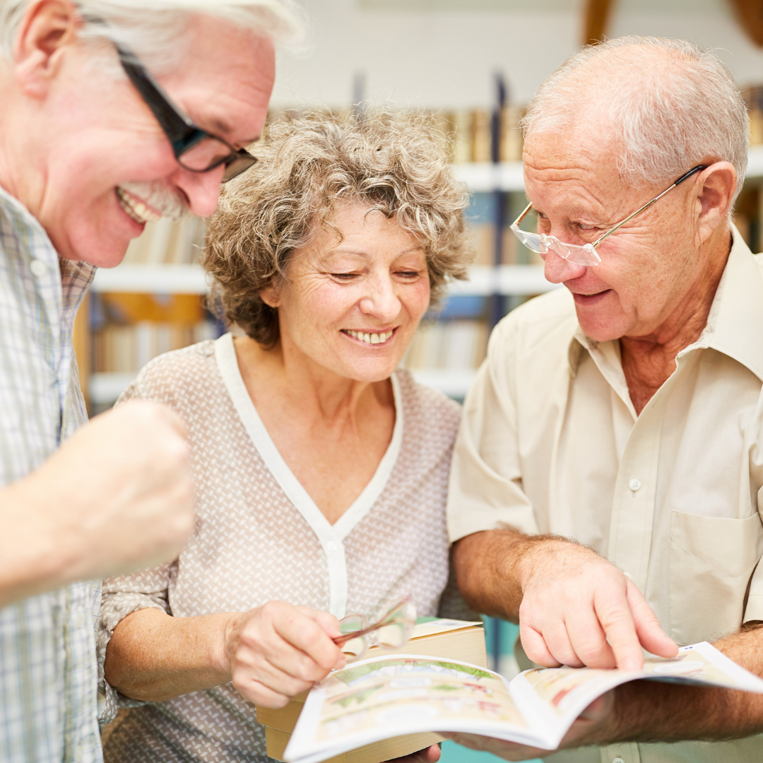 Senior woman and two senior men looking at a book together