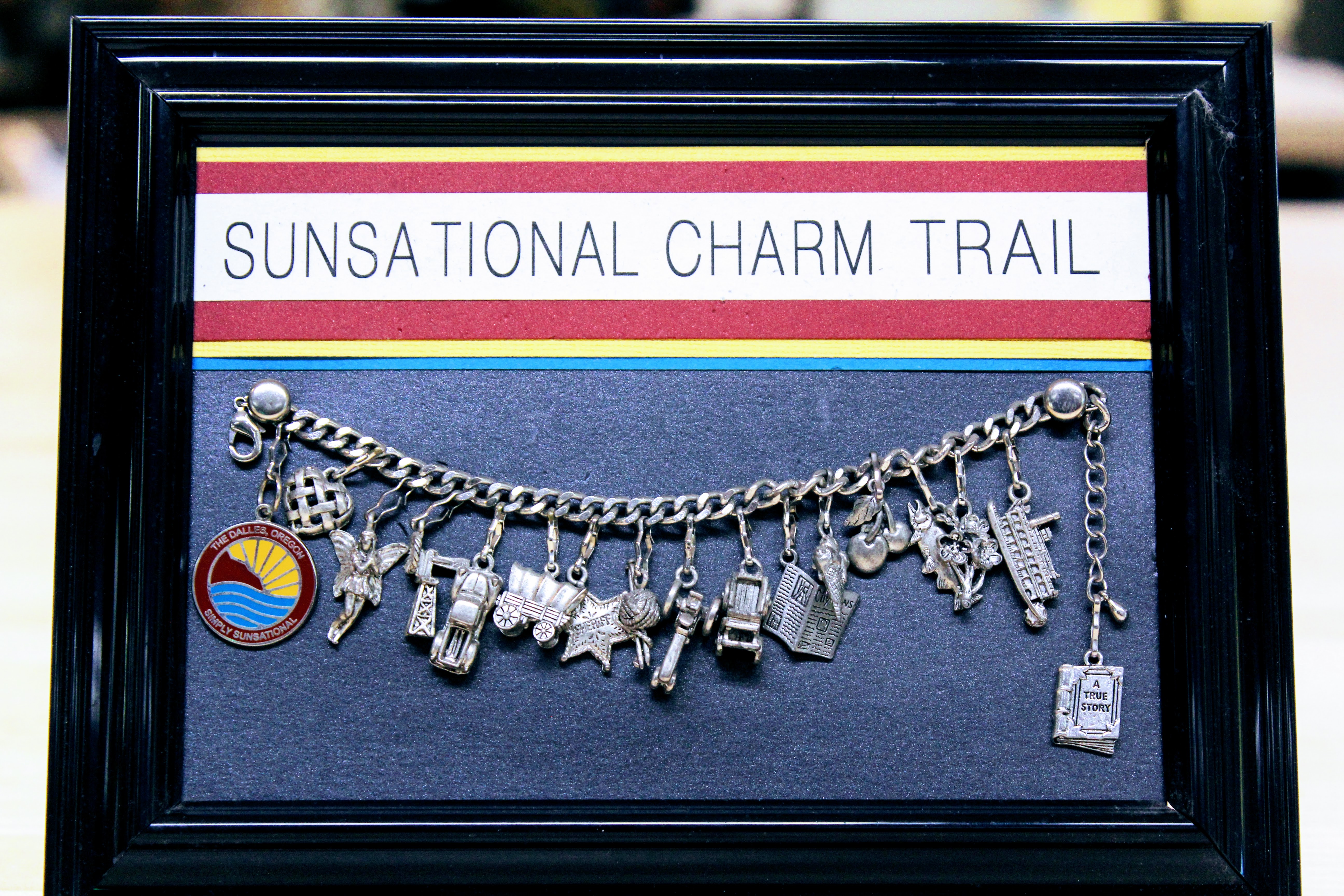 Mounted charm bracelet labelled "Sunsational Charm Trail"